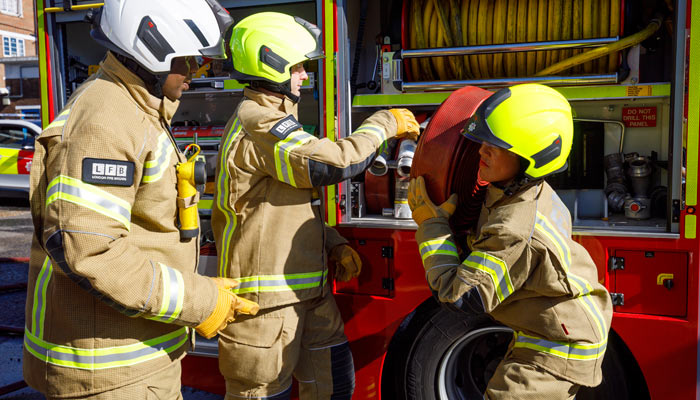 Firefighter taking a hose reel from a fire engine